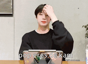 a man sitting in front of a laptop with the words pop eres de kam written on it