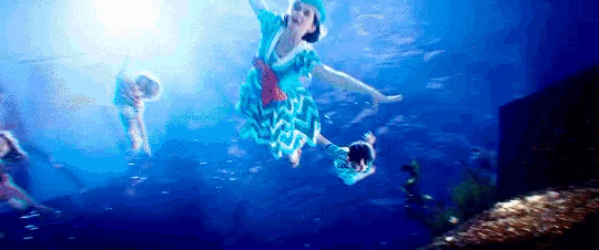 a woman in a dress is swimming underwater