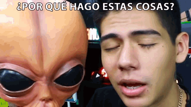 a man wearing a mask with an alien head behind him and the words por que hago estas cosas