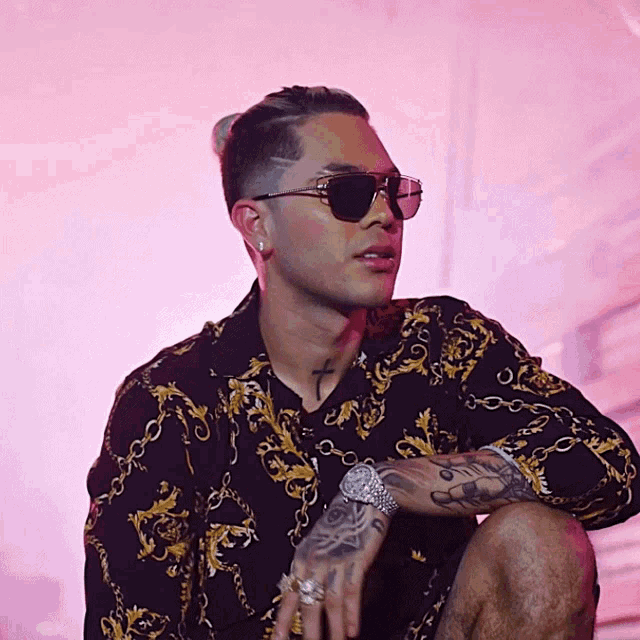 a man wearing sunglasses has a tattoo on his arm that says jesus