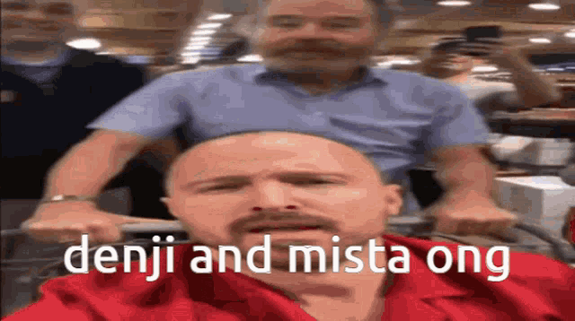 a bald man with a mustache is being pushed by another bald man in a shopping cart .