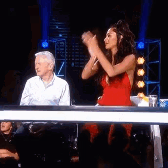 a woman in a red dress stands in front of a man