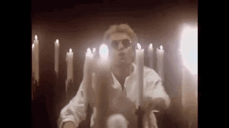 a man wearing sunglasses is holding a bunch of candles in his hands .