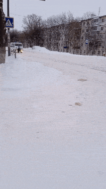 a black car is driving down a snowy street next to a white van