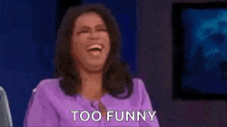 a woman in a purple shirt is laughing with her arms in the air .
