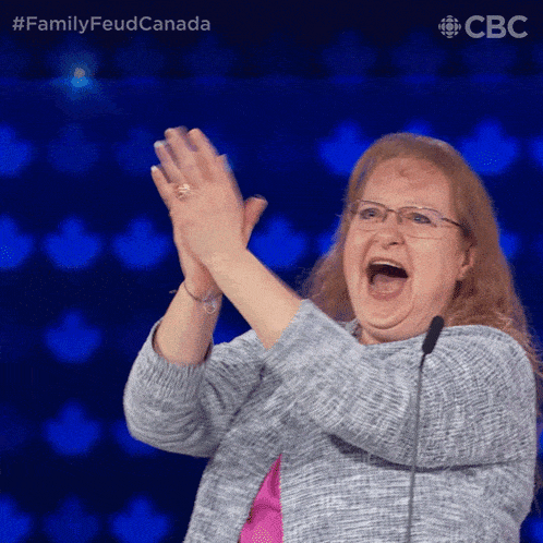 a woman applauds in front of a microphone with a cbs logo behind her