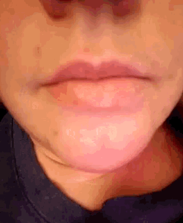 a close up of a woman 's mouth with pink lips and a blue shirt .