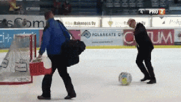 a man is kicking a soccer ball on the ice while another man watches