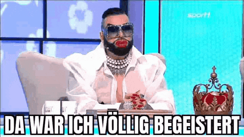 a man with a beard and sunglasses is sitting in a chair .