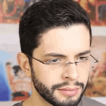 a man with a beard is wearing glasses and a gray shirt