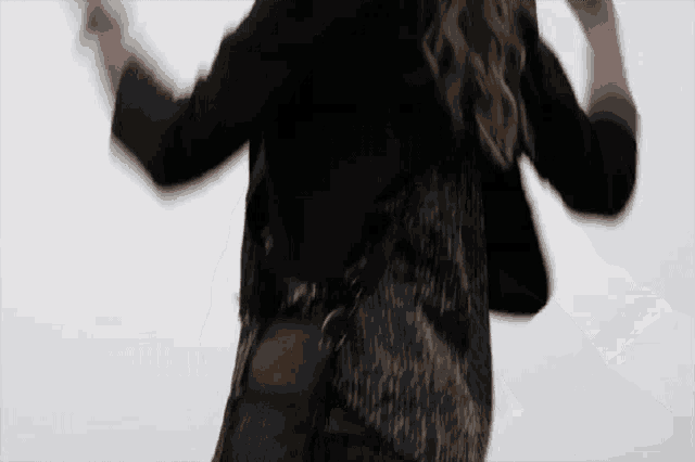 a woman in a black jacket is dancing with her arms outstretched while holding a purse .