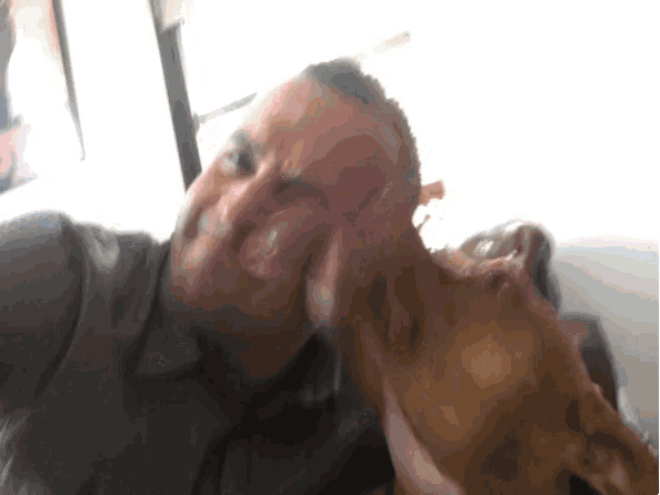 a man is sitting on a couch with a dog on his head .