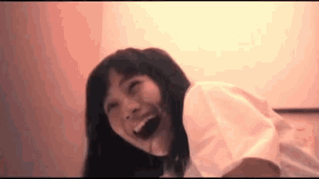 a young woman is laughing with her mouth open in a room .