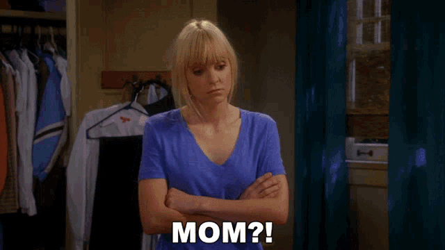 a woman in a blue shirt says mom in front of a closet full of clothes