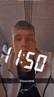 a man wearing a nike jacket is taking a selfie with the time 1:50