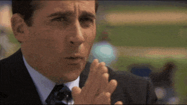 a man in a suit and tie is clapping with his hands