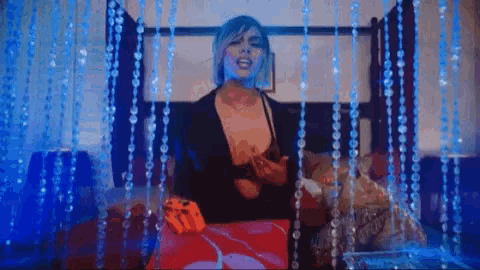 a woman in lingerie is sitting on a bed in front of a blue curtain .