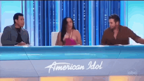 a group of people are sitting at a table with a sign that says american idol .