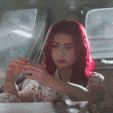 a girl with red hair is sitting in a car