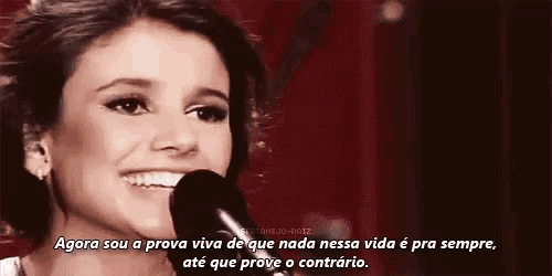 a woman is smiling and singing into a microphone with a quote in the corner .