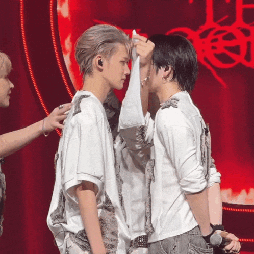 a couple of men standing next to each other on a stage with a red background