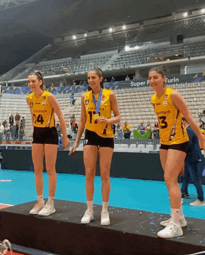 three female volleyball players standing on a podium with one wearing a number 13 jersey