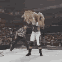 a wrestler is carrying another wrestler on his back in a ring .