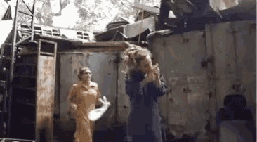 a woman with dreadlocks is standing next to another woman in front of a building .