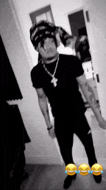 a black and white photo of a man wearing a hat and a necklace with a letter m on it