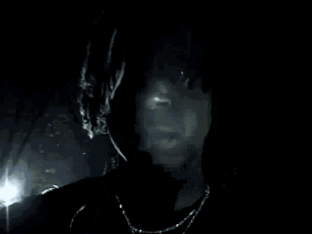 a man with dreadlocks and a chain around his neck is smoking a cigarette