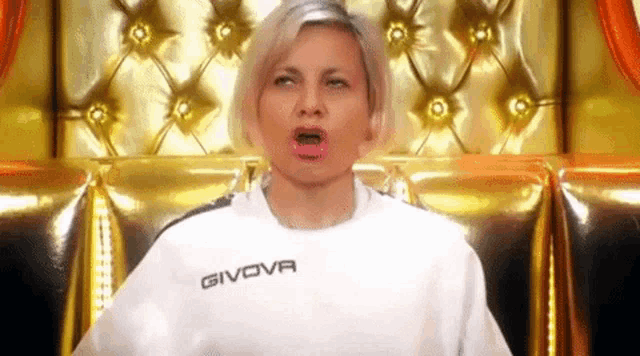 a woman wearing a givova sweatshirt is sitting on a couch .