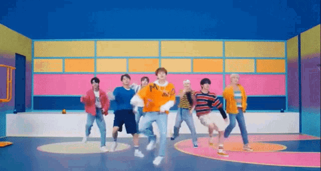 a group of young men are dancing in a room with a blue wall .