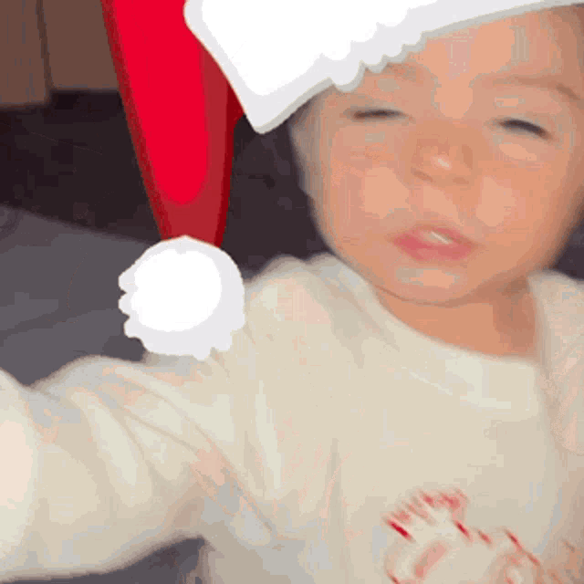 a baby wearing a santa hat and a white shirt