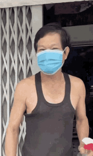 a man wearing a blue face mask and a black tank top
