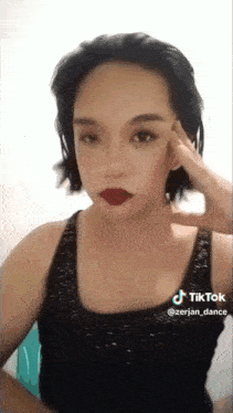 a woman wearing a black tank top and red lipstick has a tiktok sticker on her face