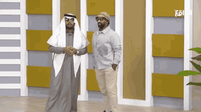 two men standing next to each other in front of a wall that says ' fg ' on it