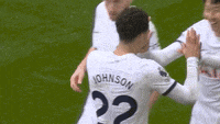 a soccer player with the number 22 on his jersey is being hugged by his teammates .