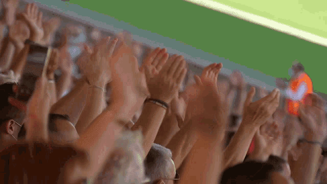 a crowd of people with their hands in the air applauding