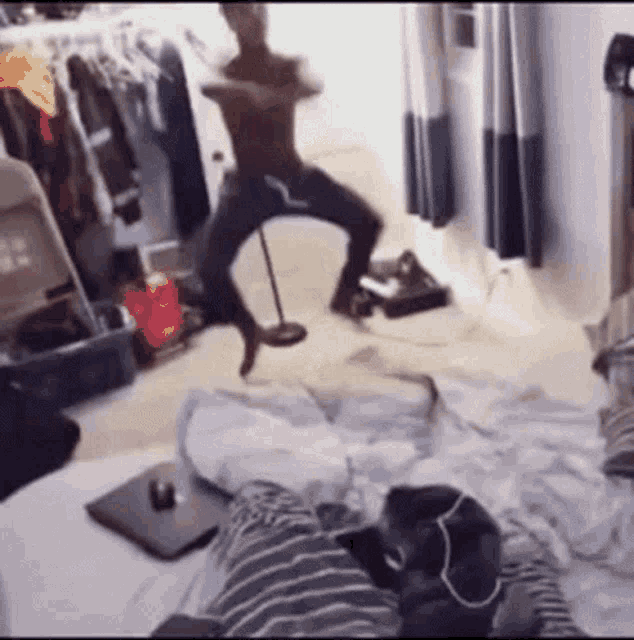 a man without a shirt is dancing in a messy room