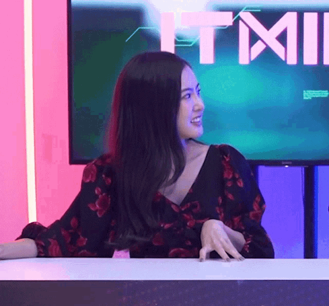 a woman sits at a table in front of a tmi logo