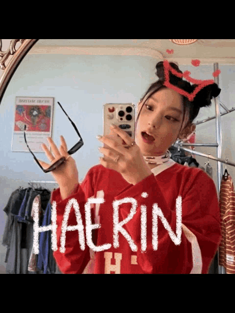 a girl is taking a picture of herself in a mirror with the name haerin written on her shirt