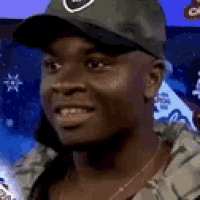 a man wearing a hat and a jacket is smiling .