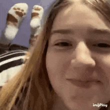 a close up of a girl 's face with her feet in the background and socks on .