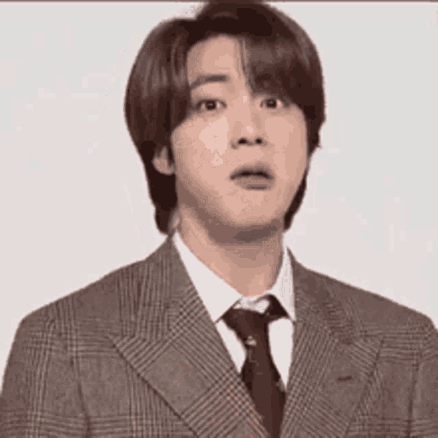 a young man in a suit and tie is making a funny face .