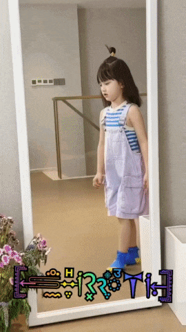 a little girl standing in front of a full length mirror with the letters h and t on it