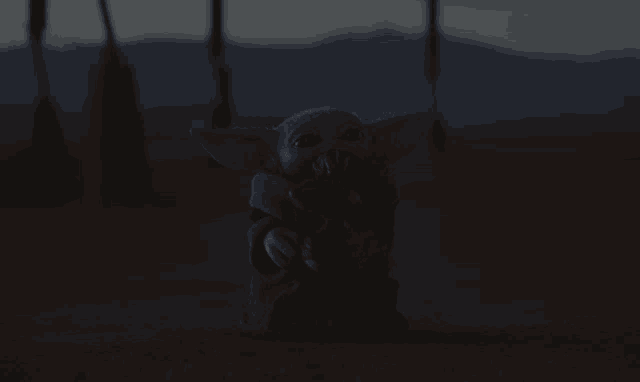 a statue of a baby yoda with a stick in his mouth