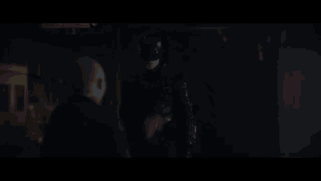 a man in a batman costume is standing next to another man in the dark
