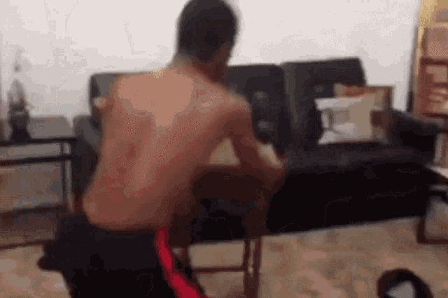 a shirtless man is sitting in a chair in front of a couch .