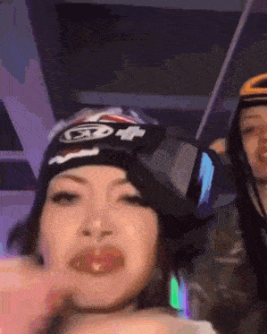 a woman wearing a virtual reality headset and a helmet with the letter t on it