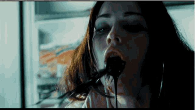 a woman is eating a piece of chocolate with a spoon in her mouth .